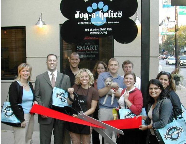 Group of people standing in front of newly opened business cutting ribbon
