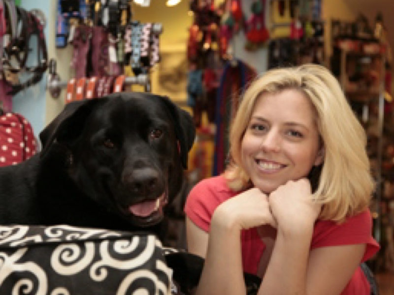 Woman posing with head on hands next to black dog