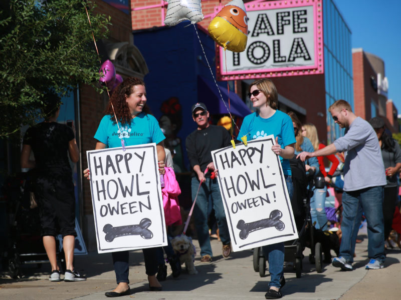 Candace D'agnolo and fellow pet business owner holding up signs that say Happy Howl-oween