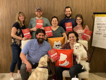 A group of pet bosses standing with Candace D'Agnolo holding up a book